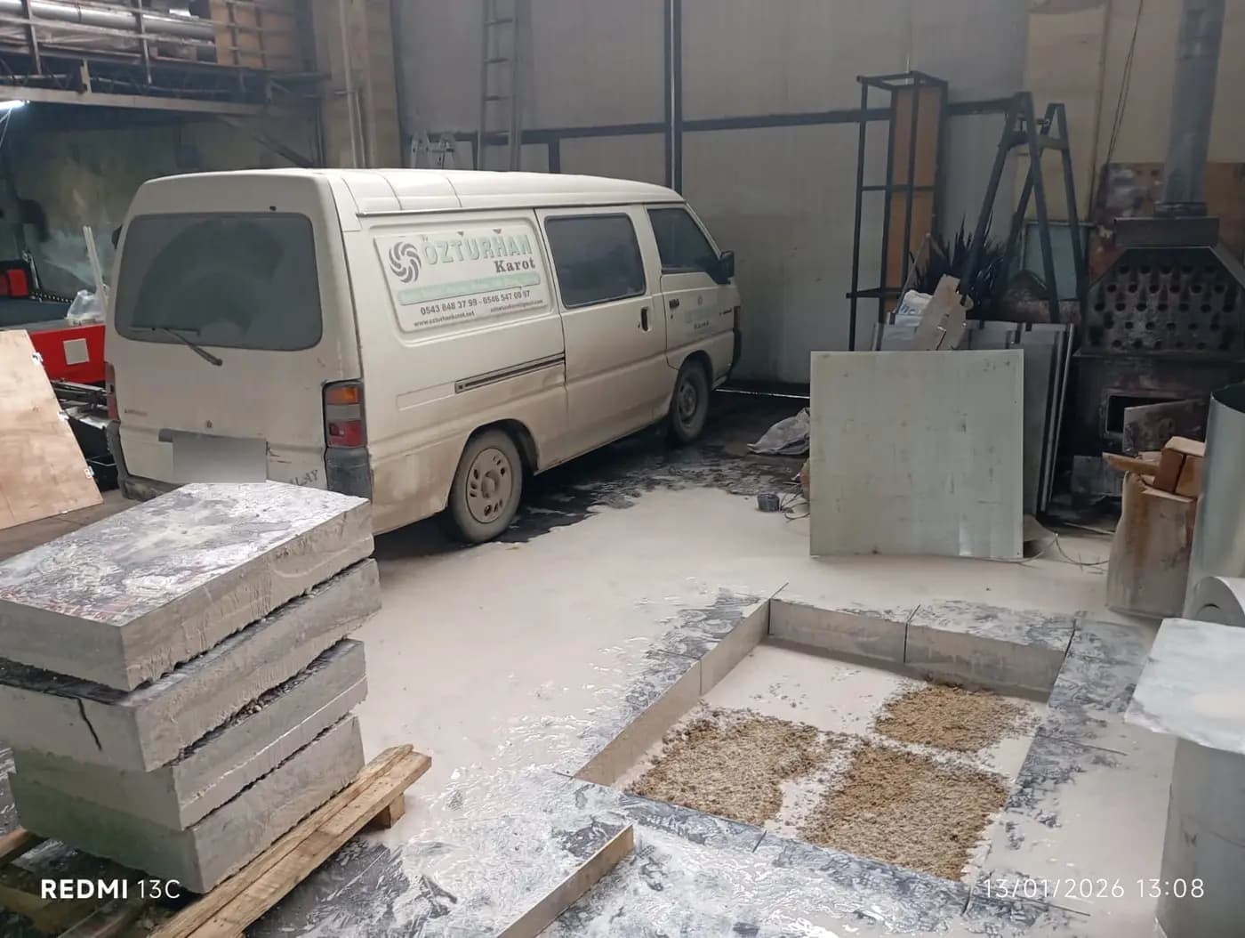 Düz kesim kenarlı zemin çukuru, tabanındaki dolgu tabakası ve paletlerde duran kalın beton bloklar