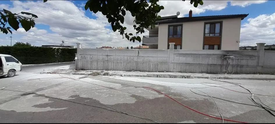 Üst panelleri alınarak alçaltılmış prefabrik bahçe duvarı ve arkadaki müstakil evin genel görünümü