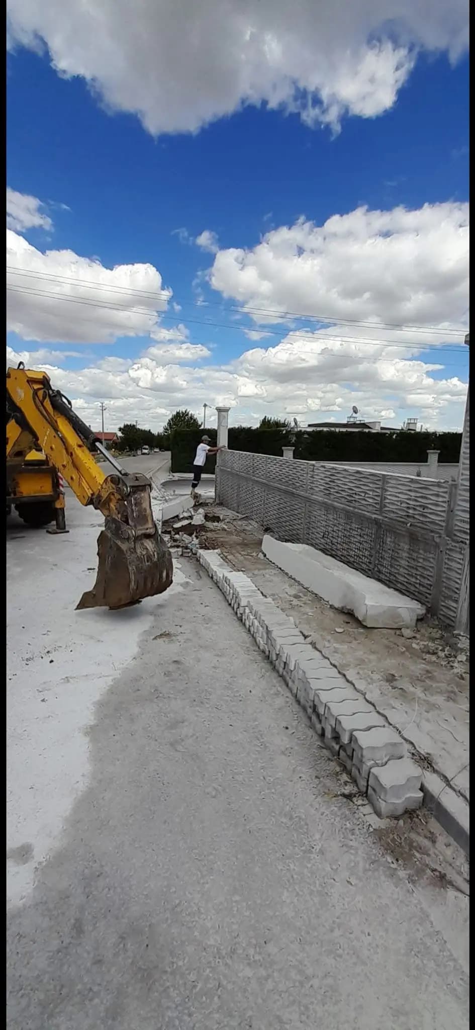 Kesilen duvar panellerini kovayla alan lastikli yükleyici ve kaldırım kenarına yatırılmış panel parçaları