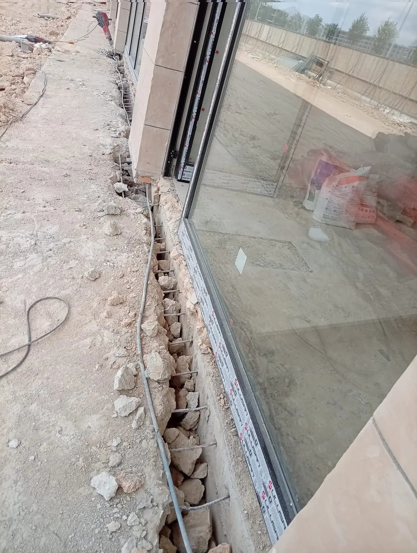 Cephe camı boyunca açılmış hendek, içinde kalan moloz ve düzenli aralıklı donatılar