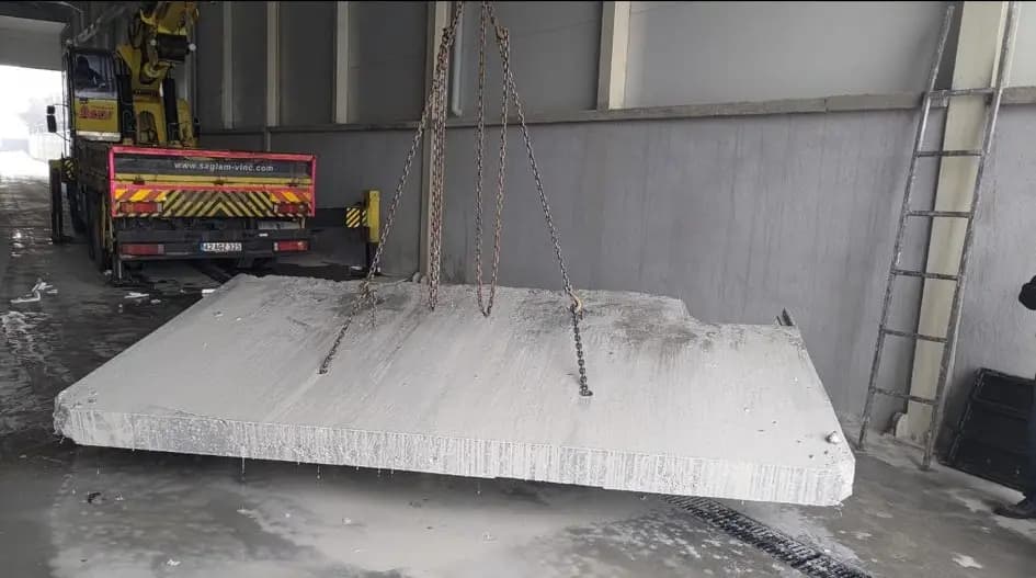 Zincirle askıya alınmış, kenarları düzgün kesilmiş büyük betonarme tabliye plakası
