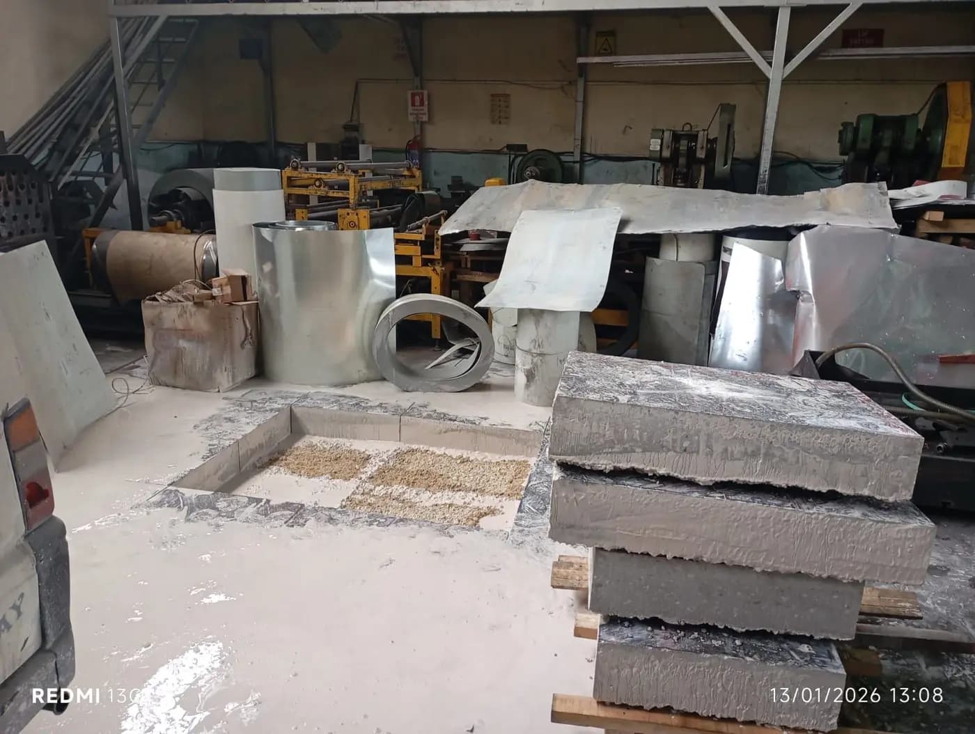 Metal işleme atölyesinde zeminde kesilerek açılmış dikdörtgen çukur ve yanında palet üzerinde istiflenmiş beton bloklar