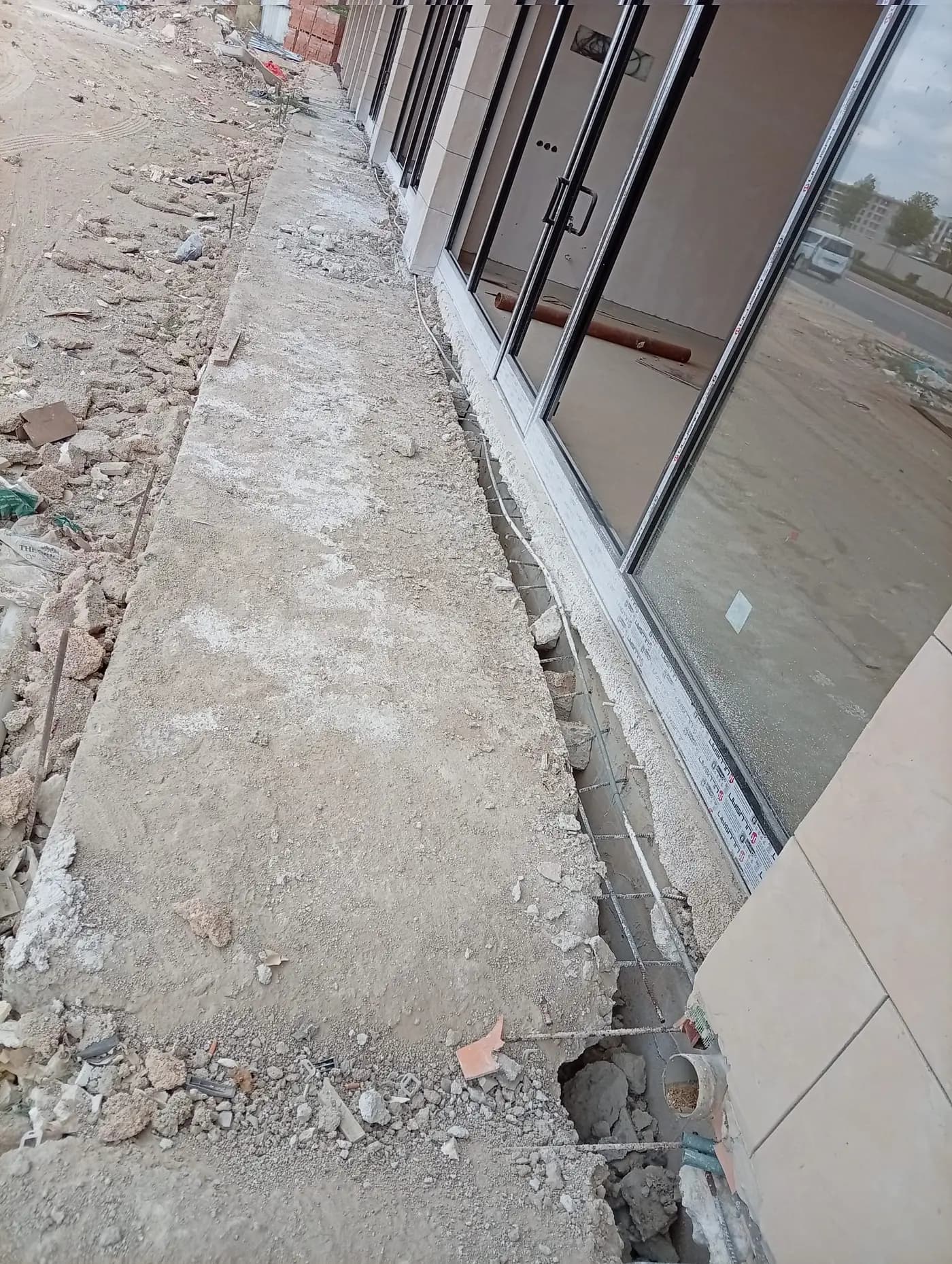 Cam cepheli bina boyunca uzanan, kenarı kırılarak donatısı açığa çıkarılmış beton şerit