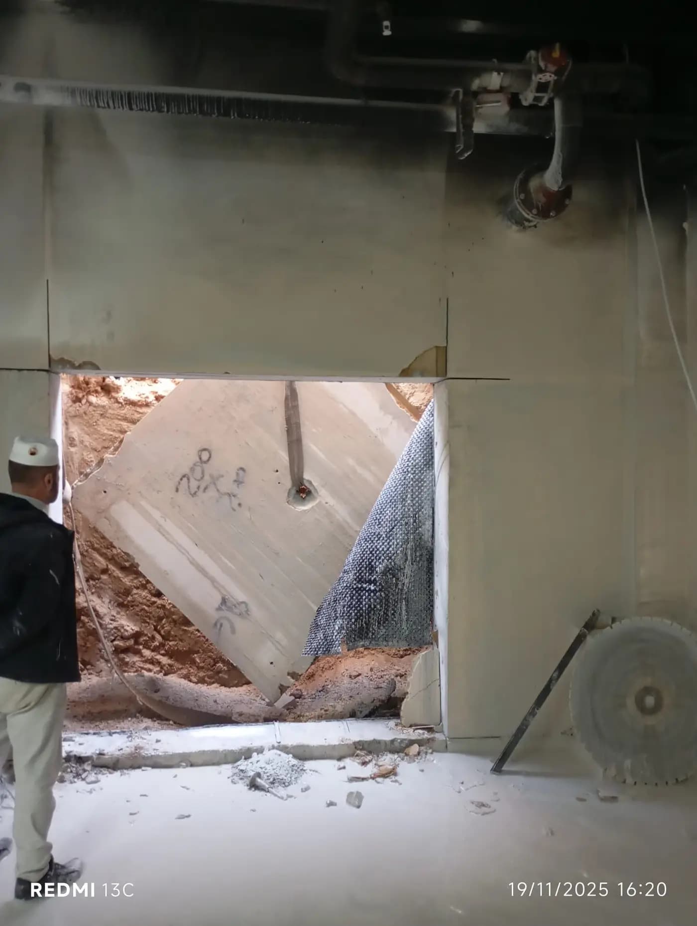 Perde duvarda açılan boşluktan dış taraftaki toprağa doğru yatırılan kesilmiş beton panel ve yanında duran elmas testere diski