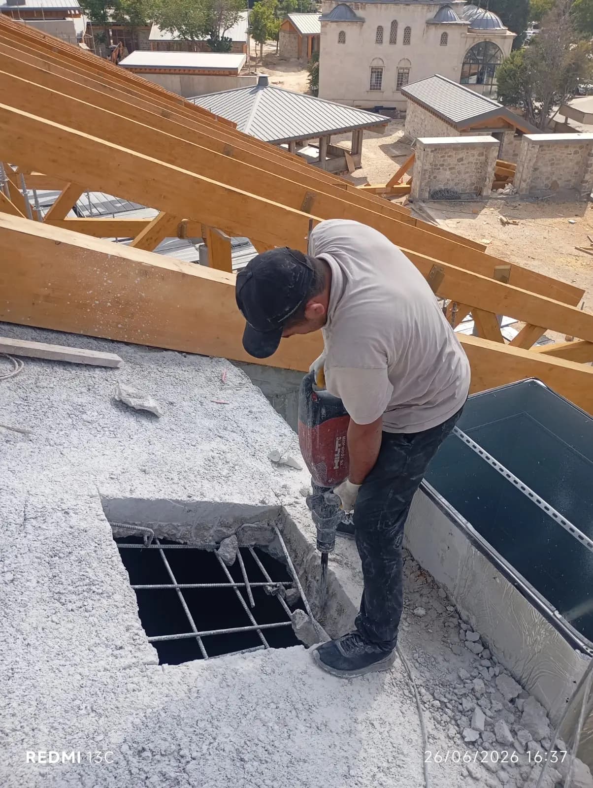 Ahşap çatı makasları kurulu binada, kırıcıyla çatı döşemesinde açılan boşluk ve açığa çıkan hasır donatı