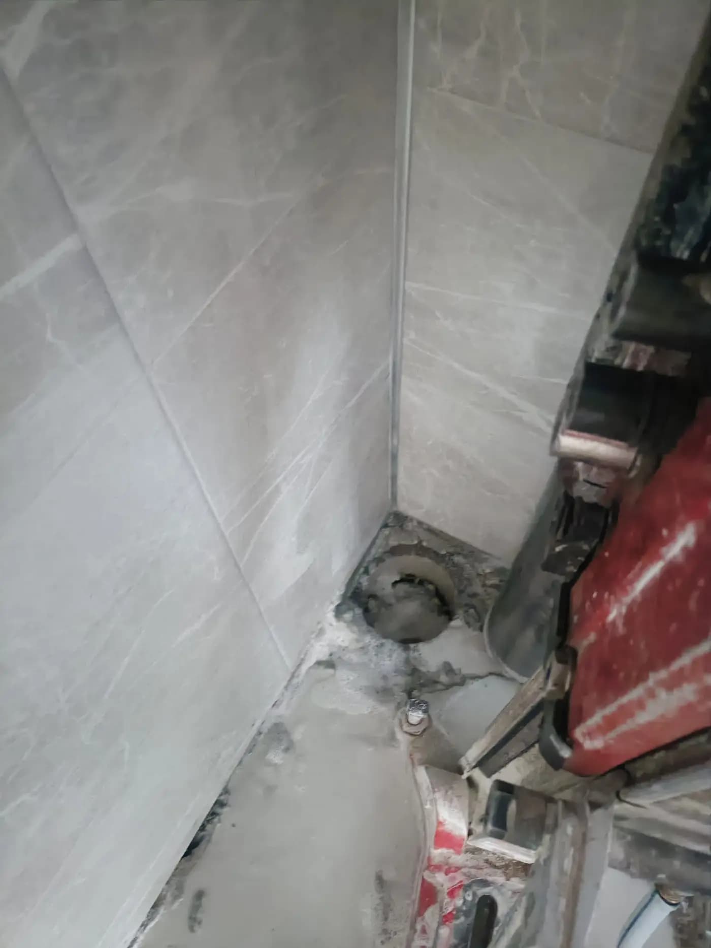 Fayans kaplı köşede döşeme kotunda açılmış karot deliği ve hemen yanında duran karot makinesi