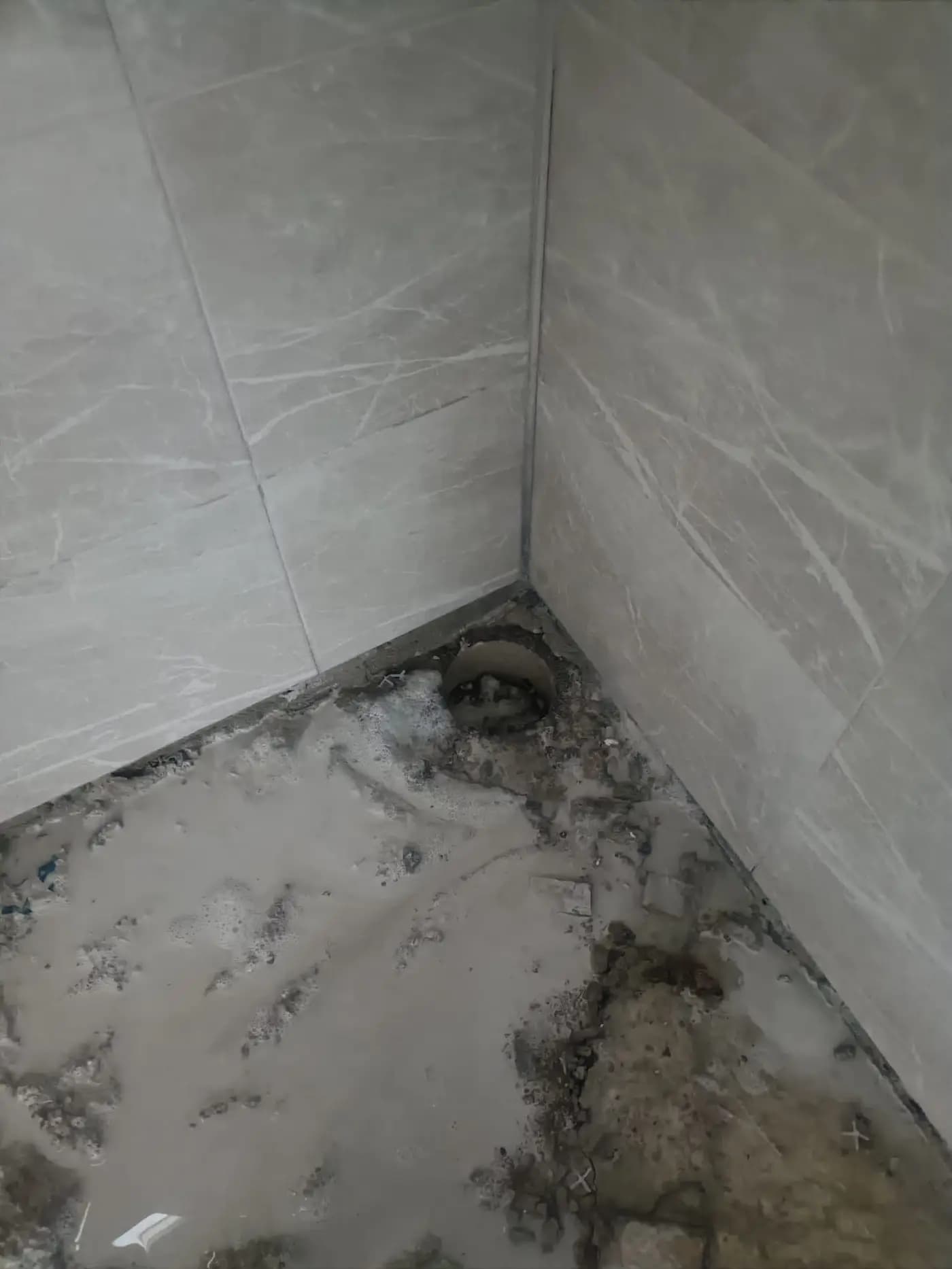 Fayans kaplı duvarın dibinde açılmış, kenarları düzgün dairesel karot deliği