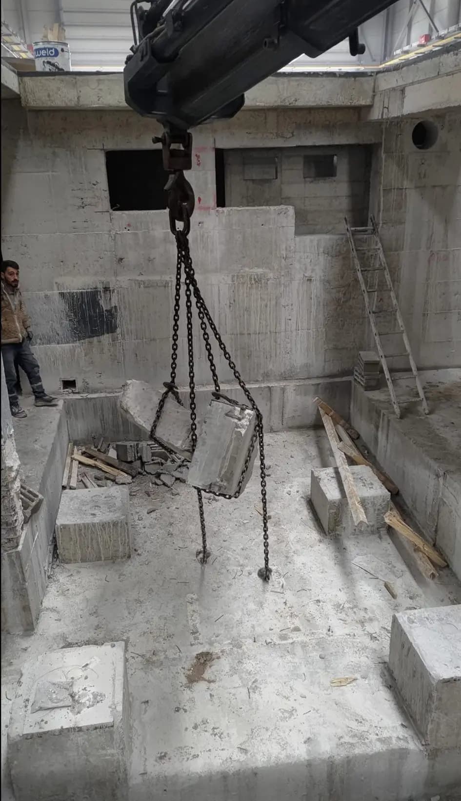 Kamyon vincinin bomu altında zincirle kaldırılan beton parça ve basamaklı betonarme yapının genel görünümü