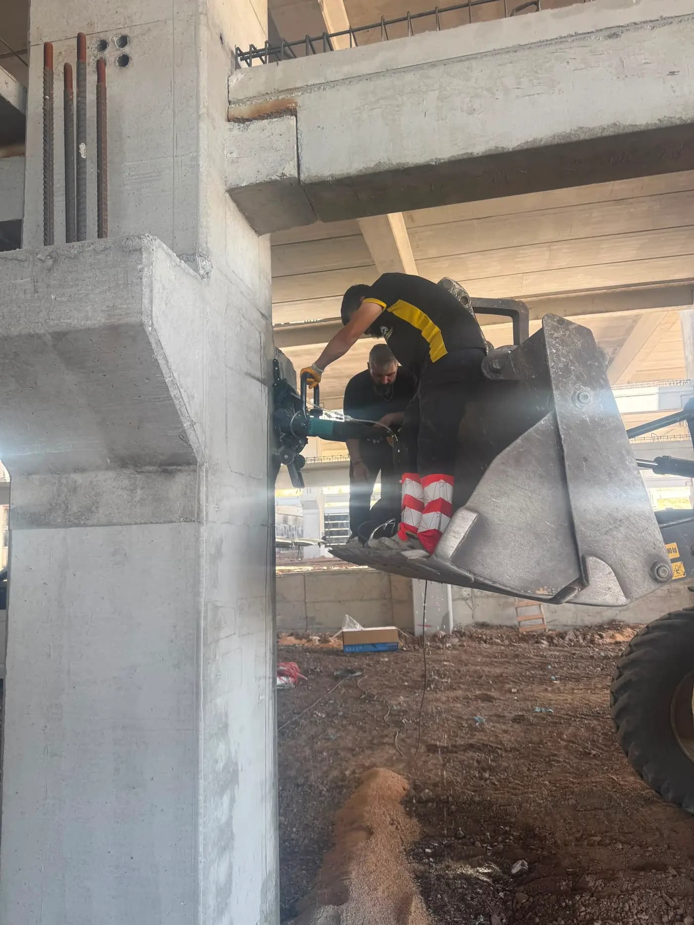 Betonarme kolona dübellenmiş kılavuz ray üzerinde çalışan raylı duvar testeresi ve kesimden akan sulu şerbet