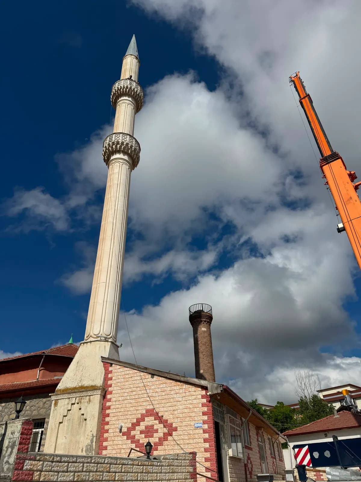 Sökümden önce yerinde duran, iki şerefeli cami minaresi ve arkada konumlanan mobil vinç bomu