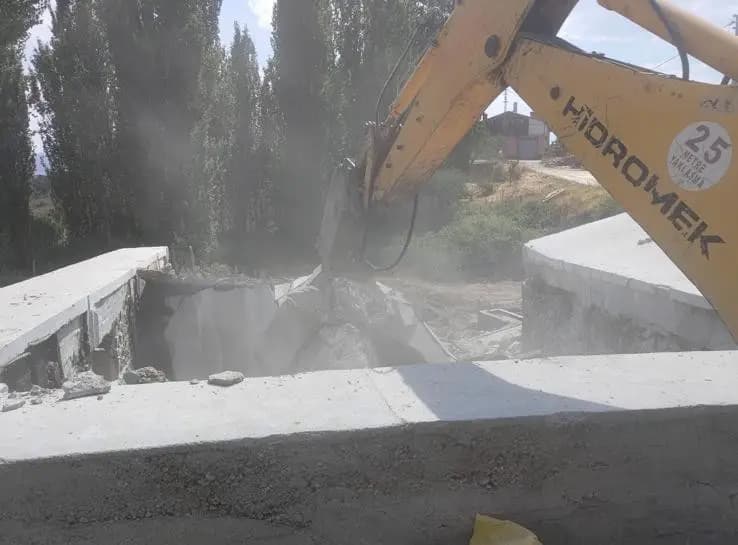 Toz bulutu içinde ikiye ayrılmış betonarme döşeme ve kırıcı ataşmanlı Hidromek ekskavatör