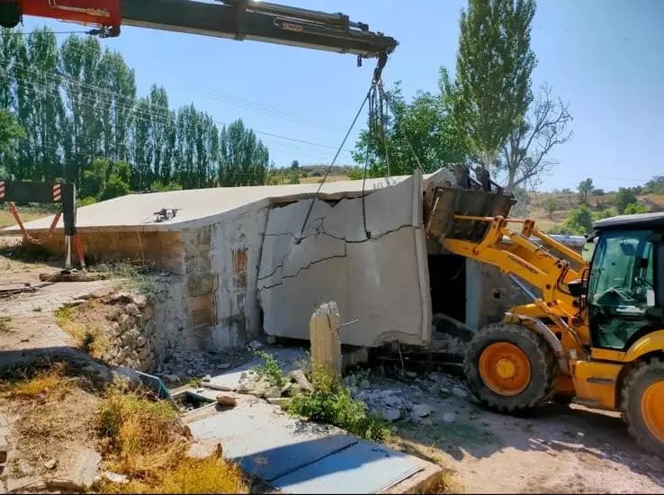 Vinç zinciriyle askıda tutulan tavan döşemesi ve yükleyici kovasıyla desteklenen söküm anı