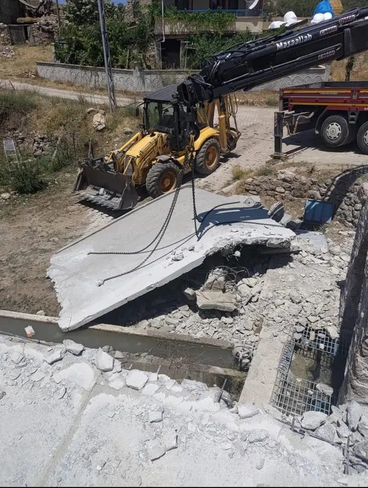 Vinçli kamyon ve yükleyiciyle kanal kenarına indirilmiş büyük betonarme döşeme parçası