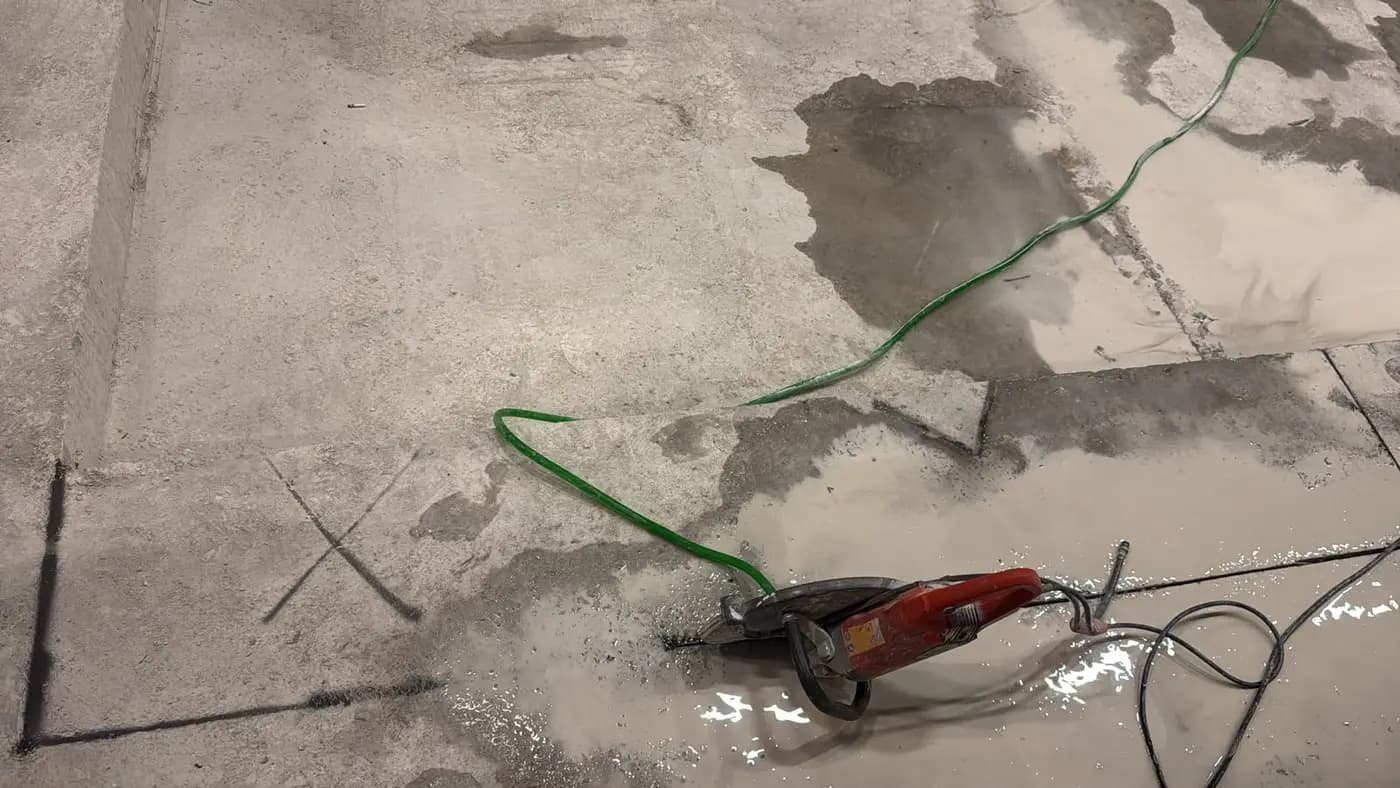 Kapalı hacimde beton zemine çarpı ile işaretlenmiş kesim noktası ve yerde duran elden kumandalı halka testere